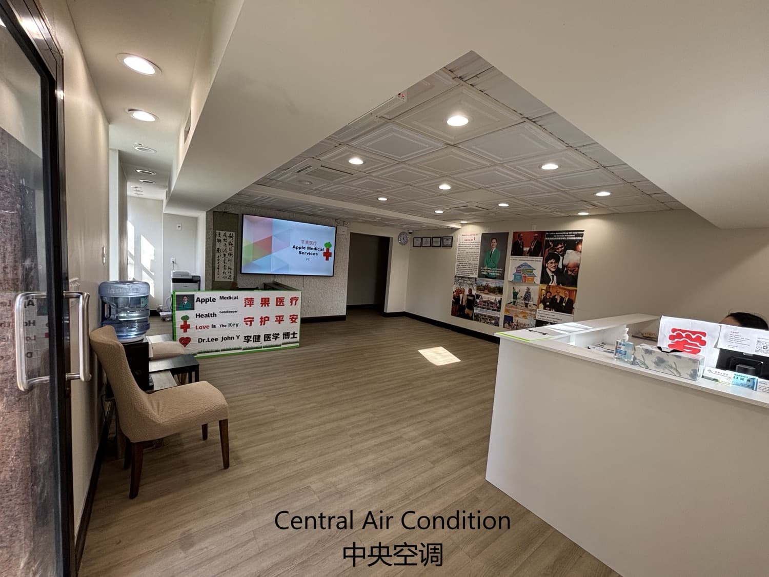 Panoramic view of the clinic lobby with a wall-mounted TV, a calligraphy scroll and the front desk