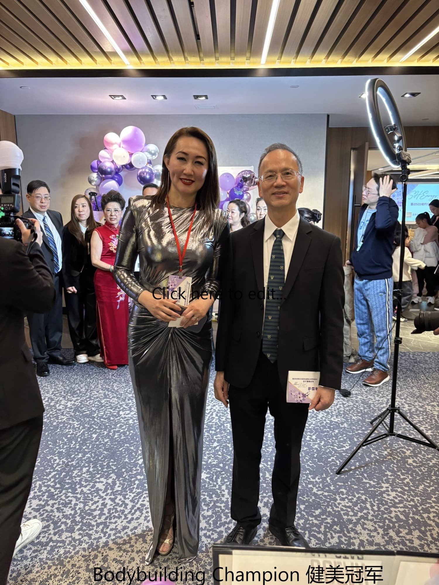 Dr. Lee in a suit posing with a female bodybuilding champion at an event